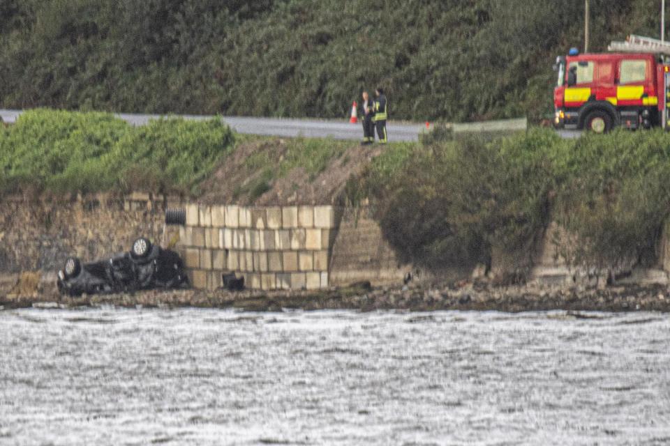 Emergency services attend to the wreckage of the car in which three people lost their lives when it entered water (PA)