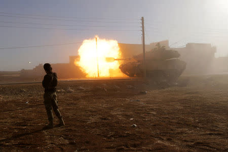 A rebel fighter stands near a Turkish tank as it fires towards Guzhe village, northern Aleppo countryside, Syria October 17, 2016. REUTERS/Khalil Ashawi