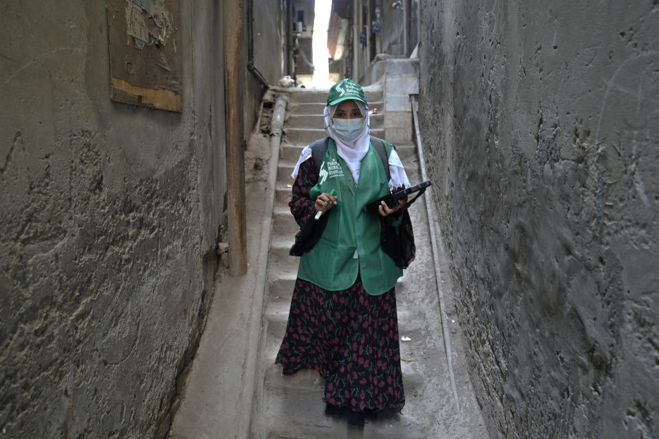 A government worker walks in a narrow alley of a neighborhood to collect data during census, in Lahore, Pakistan, Wednesday, March 1, 2023. Pakistan on Wednesday launched its first-ever digital population and housing census to gather demographic data on every individual ahead of the parliamentary elections which are due later this year, officials said. (AP Photo/K.M. Chaudary)