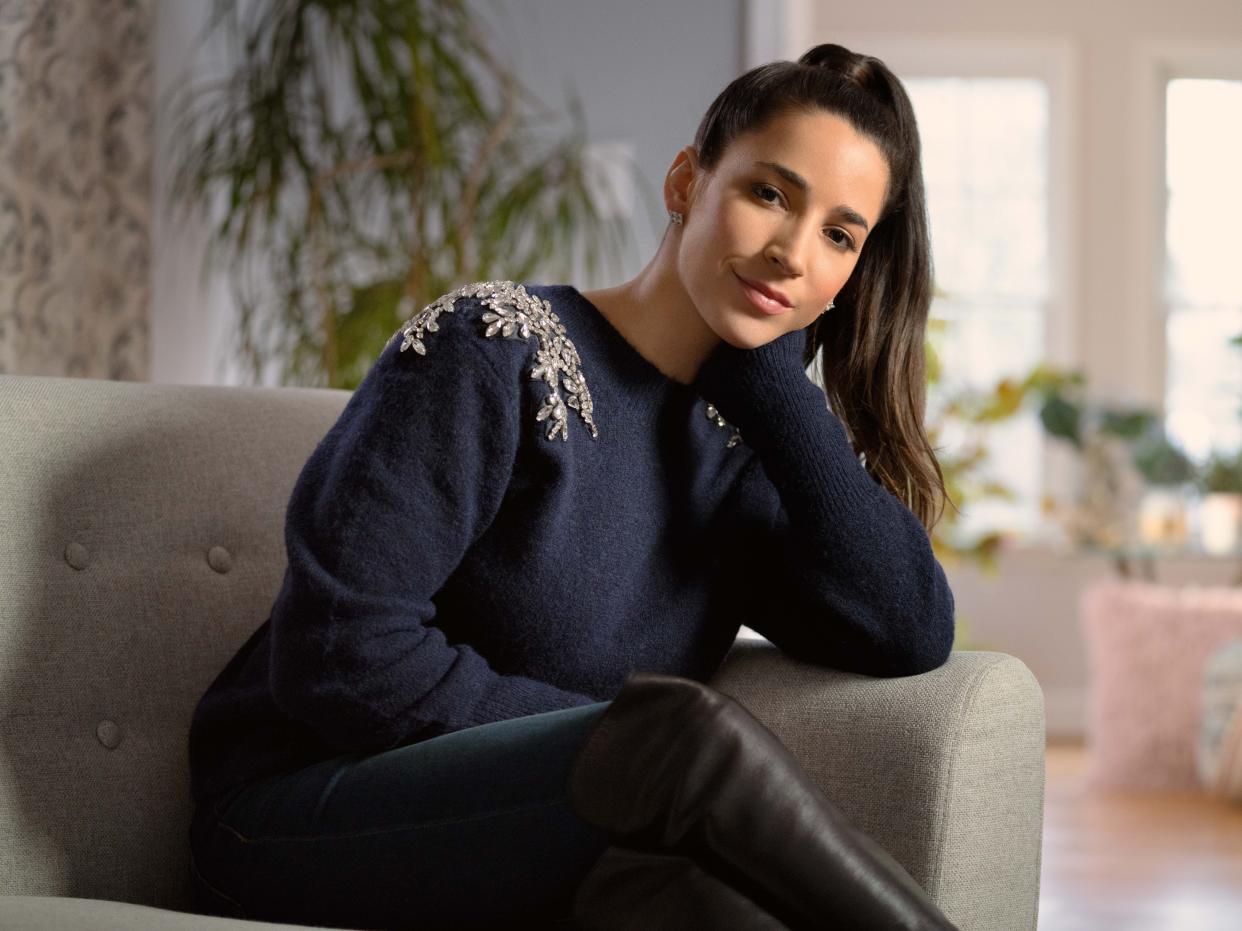 Aly Raisman sits on couch. Darkness to Light