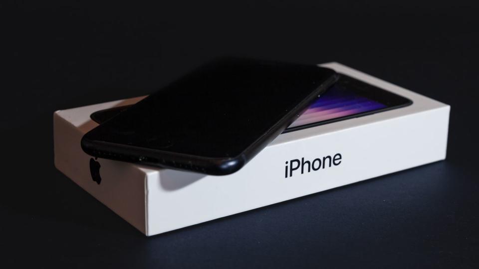 studio shot of a black iphone se3, brand new, with its box package isolated on black background released in 2022, iphone se 3 is the third generation of apple