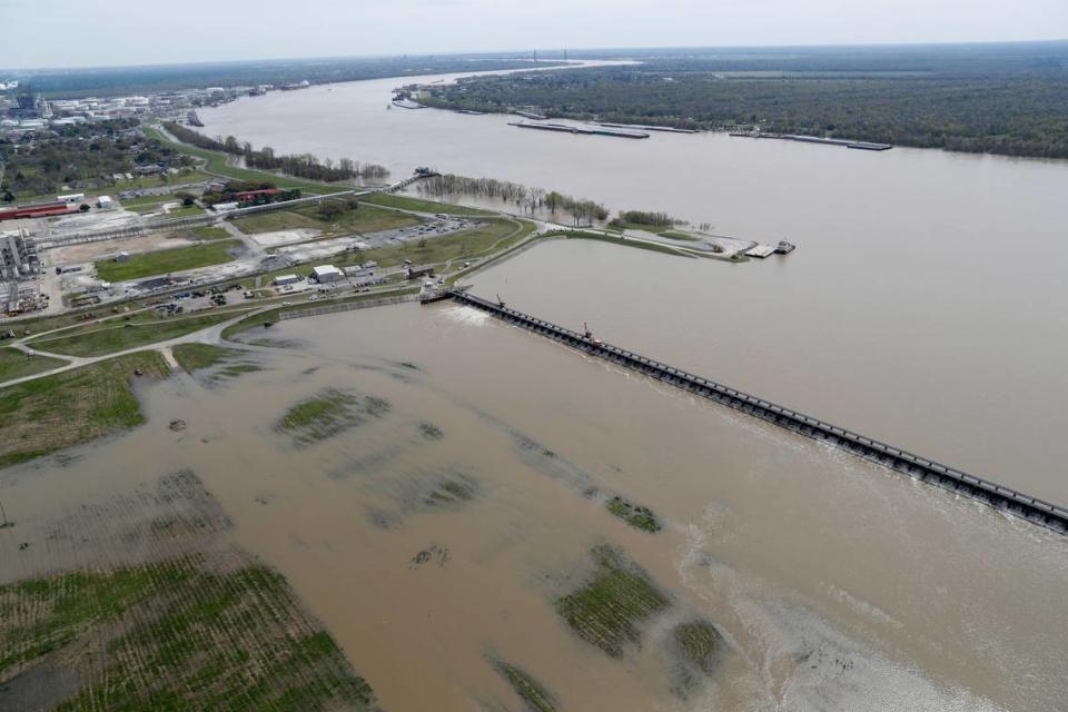 In this March 8, 2018 file photo, workers open the gates of the Bonnet Carre spillway, which diverts water from the rising Mississippi River, above right, to Lake Pontchartrain. The Corps has opened the spillway a record number of times in recent years to prevent flooding in New Orleans.