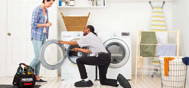 Member of Best Buy Geek Squad installing a washer and dryer.