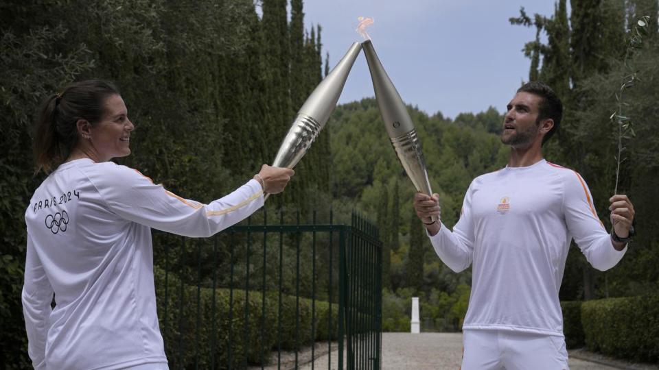 Stefanos Douskos (right) passes the flame to France's Laure Manaudou