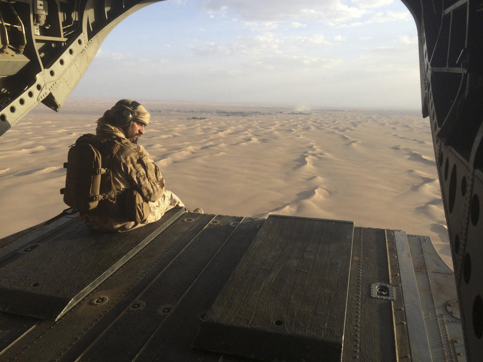 File - In this Thursday, Sept. 17, 2015. file photo, Aan Emirati gunner watches for enemy fire from the rear gate of a United Arab Emirates Chinook military helicopter flying over Yemen. The United Arab Emirates has begun to draw down its forces in past weeks in 2019, leaving the Saudi-led coalition with a weakened ground presence and fewer tactical options. The withdrawal of several thousand troops comes amid heightened tensions between the United States and Iran, and as the Iranian-allied Yemeni rebels known as Houthis increase their attacks on Saudi Arabia.(AP Photo/Adam Schreck, File)