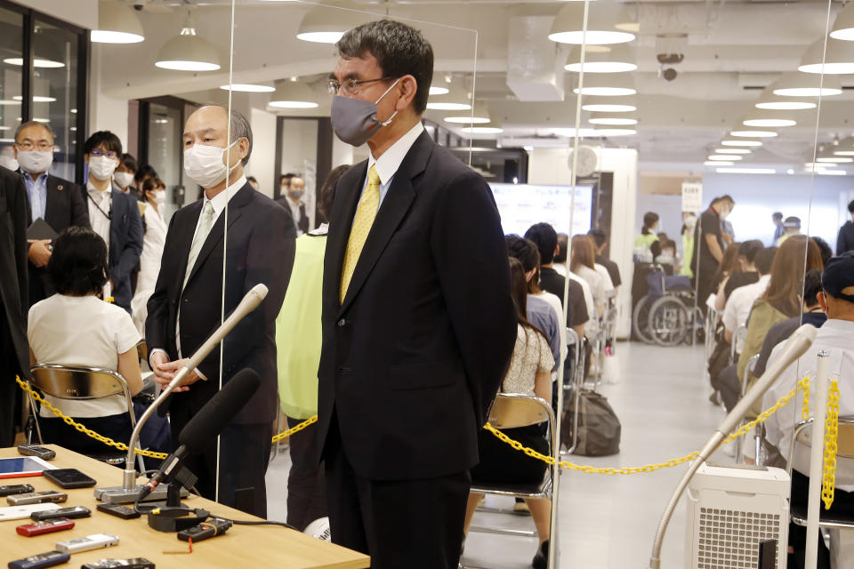Covid 19 Vaccine Minister Taro Kono, center, and Masayoshi Son, chief executive of technology company SoftBank Group Corp., left, speak to media after visiting an inoculation site set up by Japanese technology company SoftBank Group Corp. at a WeWork office Tuesday, June 15, 2021, in Tokyo. Japanese companies have joined the effort to speed up the country’s lagging coronavirus vaccine rollout before the Tokyo Olympics begin next month. (AP Photo/Yuri Kageyama)