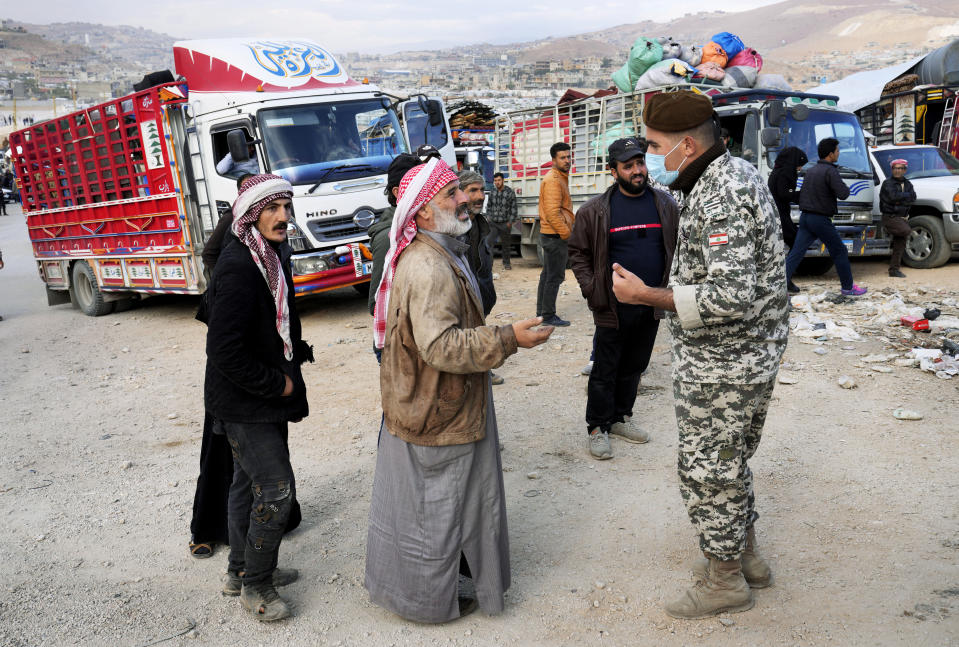 A Syrian refugee man, left, speaks with a Lebanese General Security officer, right, at a gathering point where they prepare to back home to Syria, in the eastern Lebanese border town of Arsal, Lebanon, Wednesday, Oct. 26, 2022. Several hundred Syrian refugees boarded a convoy of trucks laden with mattresses, water and fuel tanks, bicycles – and, in one case, a goat – Wednesday morning in the remote Lebanese mountain town of Arsal in preparation to return back across the nearby border.(AP Photo/Hussein Malla)