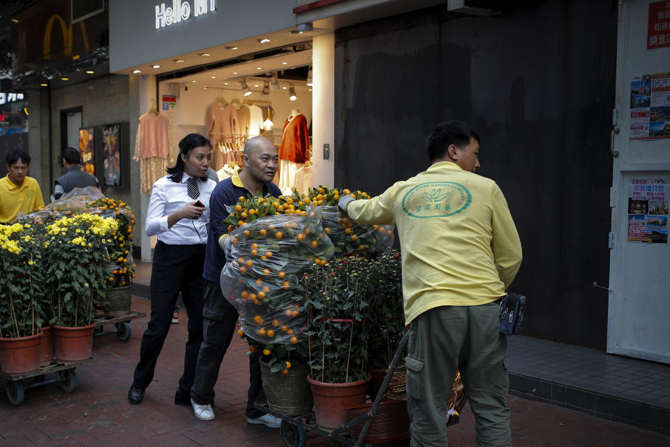 Workers push carts loaded with mandarin orange plants and flowers to their customer passing by a closed shop lot covered with steel panel in Hong Kong, Saturday, Jan. 4, 2020. City's businesses has been hit badly following the months-long pro-democracy movement has extended into 2020 with further mass demonstrations. (AP Photo/Andy Wong)