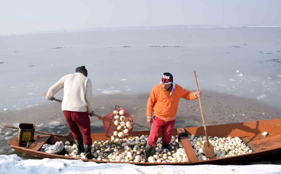 A vegetable vendor breaks the sheet of ice covering the Dal Lake in order to row his boat.