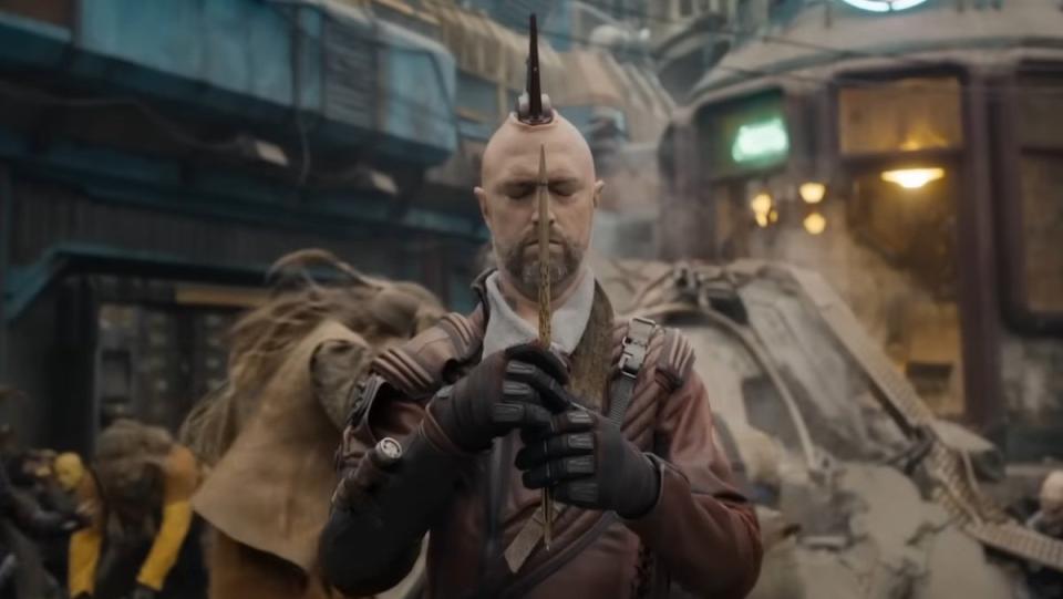 Kraglin closes his eyes and holds his arrow as people run around him in Guardians of the Galaxy Vol. 3
