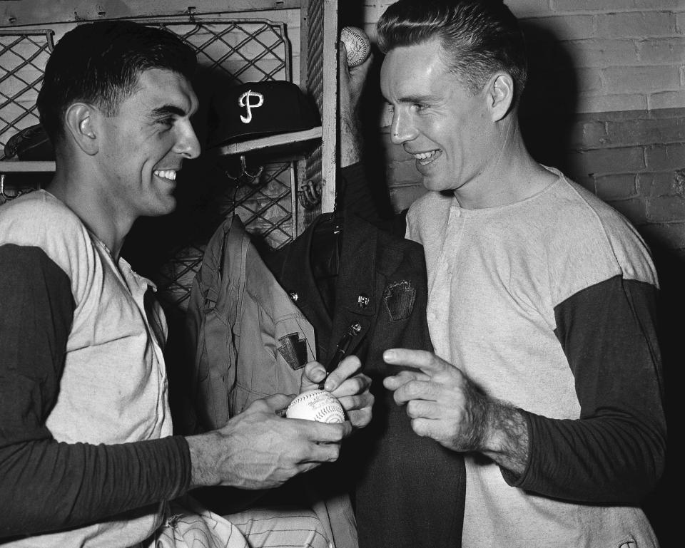 FILE - Philadelphia Phillies' Curt Simmons, left, autographs a ball for teammate John "Jocko" Thompson before Game 1 of the World Series against the New York Yankees at Shibe Park in Philadelphia, Oct. 4, 1950. Simmons, the last surviving member of the 1950 Philadelphia Phillies “Whiz Kids” team, died Tuesday, Dec. 13, 2022 in Ambler, Pa. He was 93. (AP Photo/File)