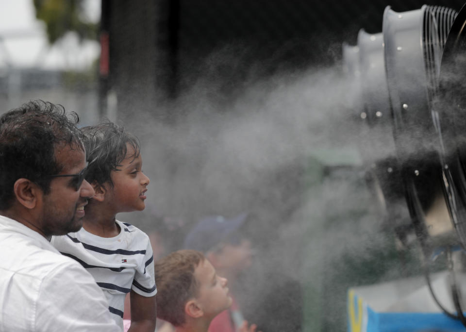 Fans cool down during events ahead of the Australian Open tennis championship in Melbourne, Australia, Saturday, Jan. 18, 2020. (AP Photo/Lee Jin-man)