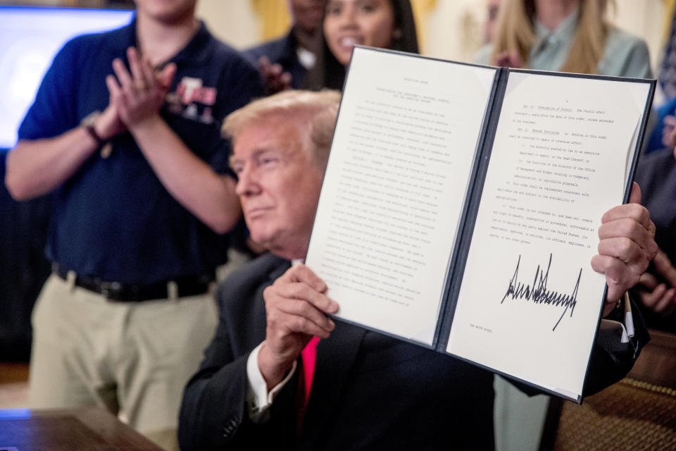 President Donald Trump, surrounded by workers, holds up an Executive Order that establishes a National Council for the American Worker after signing it during a ceremony in the East Room of the White House, Thursday, July 19, 2018, in Washington. (AP Photo/Andrew Harnik)