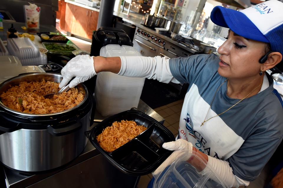 Nardin Barwari serves seafood rice at Ocean Delight located inside the Nashville Farmers Market on Thursday, July 27, 2023, in Nashville, Tenn. Ocean Delight uses the test kitchen in the market house to operate. It is one of several kitchens around town that support local chefs trying to start their own businesses.