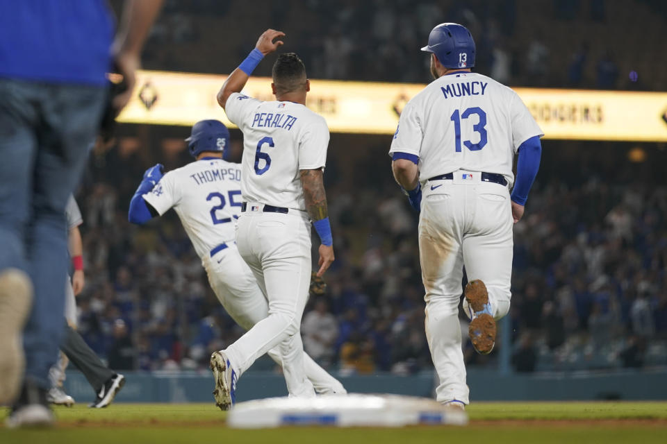 Los Angeles Dodgers' Trayce Thompson (25) runs away from David Peralta (6) and tMax Muncy (13) after he walked, allowing Chris Taylor to score and win the game 9-8 against the Minnesota Twins in a baseball game in Los Angeles, Monday, May 15, 2023. (AP Photo/Ashley Landis)