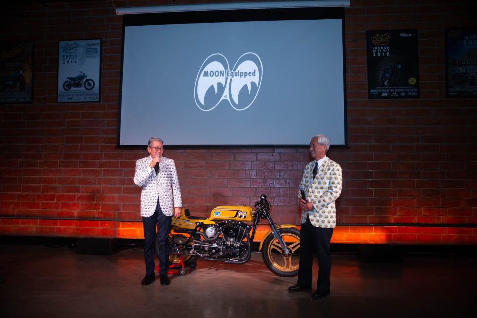 a couple of men standing next to a motorcycle in front of a building