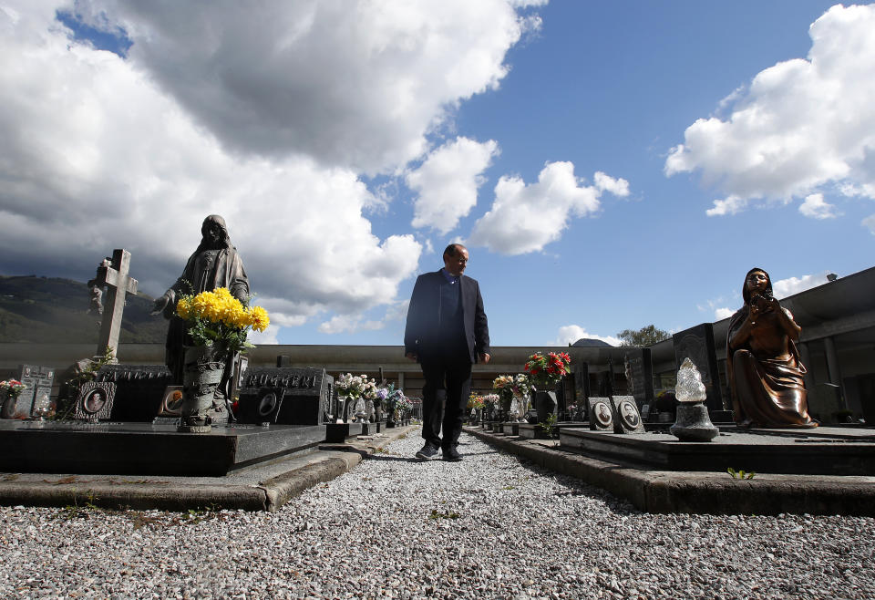 FILE - In this Sunday, Sept. 27, 2020 file photo, Rev. Mario Carminati walks in a cemetery in Casnigo, near Bergamo, Italy. After the European Union passed the death toll of half a million citizens lost to the coronavirus on Wednesday, Feb. 10, 2021, the EU Commission chief said that stalling rollout of the vaccines could be partly blamed on the bloc being over-optimistic, over-confident and plainly "too late." (AP Photo/Antonio Calanni, File)