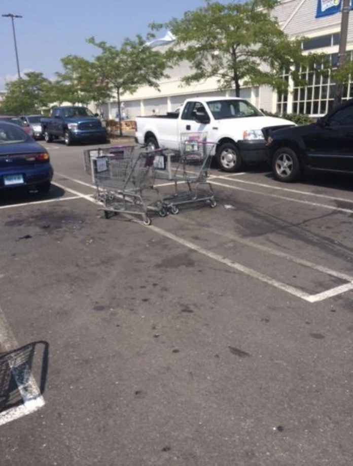 Two shopping carts left in a parking space outside a store