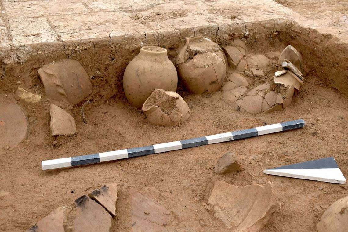 Pottery vessels with cuneiform writing tablets inside stand in the corner of what used to be a storage room.