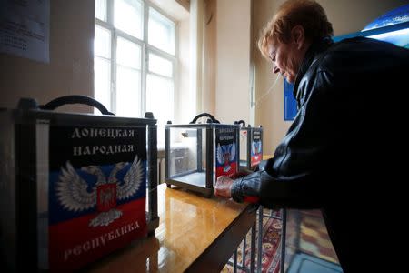 A member of a local electoral commission takes part in the preparations for the upcoming election, with stickers displaying symbols of the self-proclaimed Donetsk People's Republic seen on ballot boxes, at a polling station in Donetsk, eastern Ukraine, October 31, 2014. REUTERS/Maxim Zmeyev