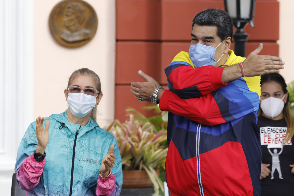 Venezuelan President Nicolas Maduro gestures a hug to supporters during an event with his wife Cilia Flores marking Youth Day at Miraflores presidential palace in Caracas, Venezuela, Friday, Feb. 12, 2021, amid the COVID-19 pandemic. The annual holiday commemorates young people who accompanied heroes in the battle for Venezuela's independence. (AP Photo/Ariana Cubillos)