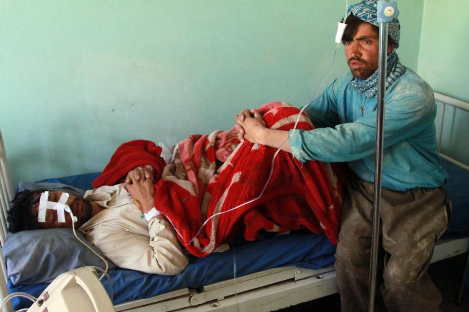 An Afghan man, right, sits by his cousin who was injured in an attack, at a hospital in Ghazni city, Afghanistan, Monday, May 12, 2014. The attacks happened on the outskirts of the city in the province by the same name, said deputy provincial governor, Mohammad Ali Ahmadi. Two women and a policeman were killed, while two policemen and six civilians, including three children, were wounded, added Ahmadi. (AP Photo/Rahmatullah Nikzad)