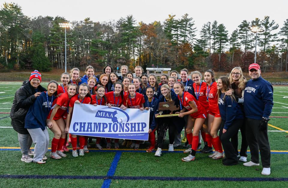 Natick players celebrate with the championship banner and trophy at the conclusion of the Division 1 state final.