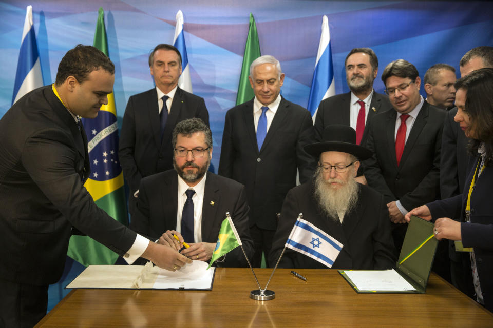 Prime Minister Benjamin Netanyahu, center, and Brazilian President Jair Bolsonaro, second left standing, watch as numerous economic agreements are signed by their ministers, at the prime minister's office in Jerusalem, Sunday, March 31, 2019. (Heidi Levine/Pool Photo via AP)