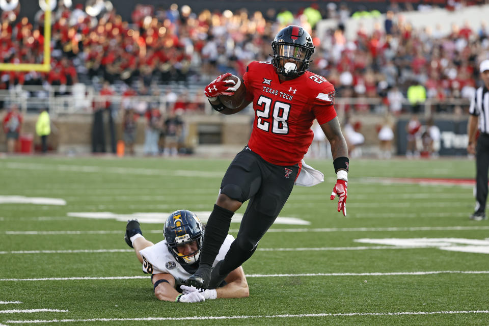Texas Tech's Tahj Brooks (28) tries to break away from Murray State's Cade Shupperd during the first half of an NCAA college football game Saturday, Sept. 3, 2022, in Lubbock, Texas. (AP Photo/Brad Tollefson)