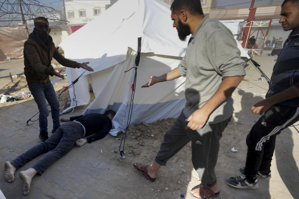 Palestinians stand around a man killed on the Al-Aqsa Hospital grounds after an Israeli strike hit a building next to it, in Deir al Balah, Gaza Strip, on Wednesday, Jan 10, 2023. (AP Photo/Adel Hana)