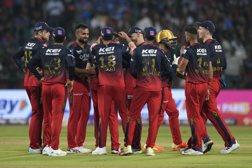 Royal Challengers Bangalore players celebrate the dismissal of Mumbai Indians' Tim David during the Indian Premier League cricket match between Royal Challengers Bangalore and Mumbai Indians in Bengaluru, India, Sunday, April 2, 2023. (AP Photo/Aijaz Rahi)