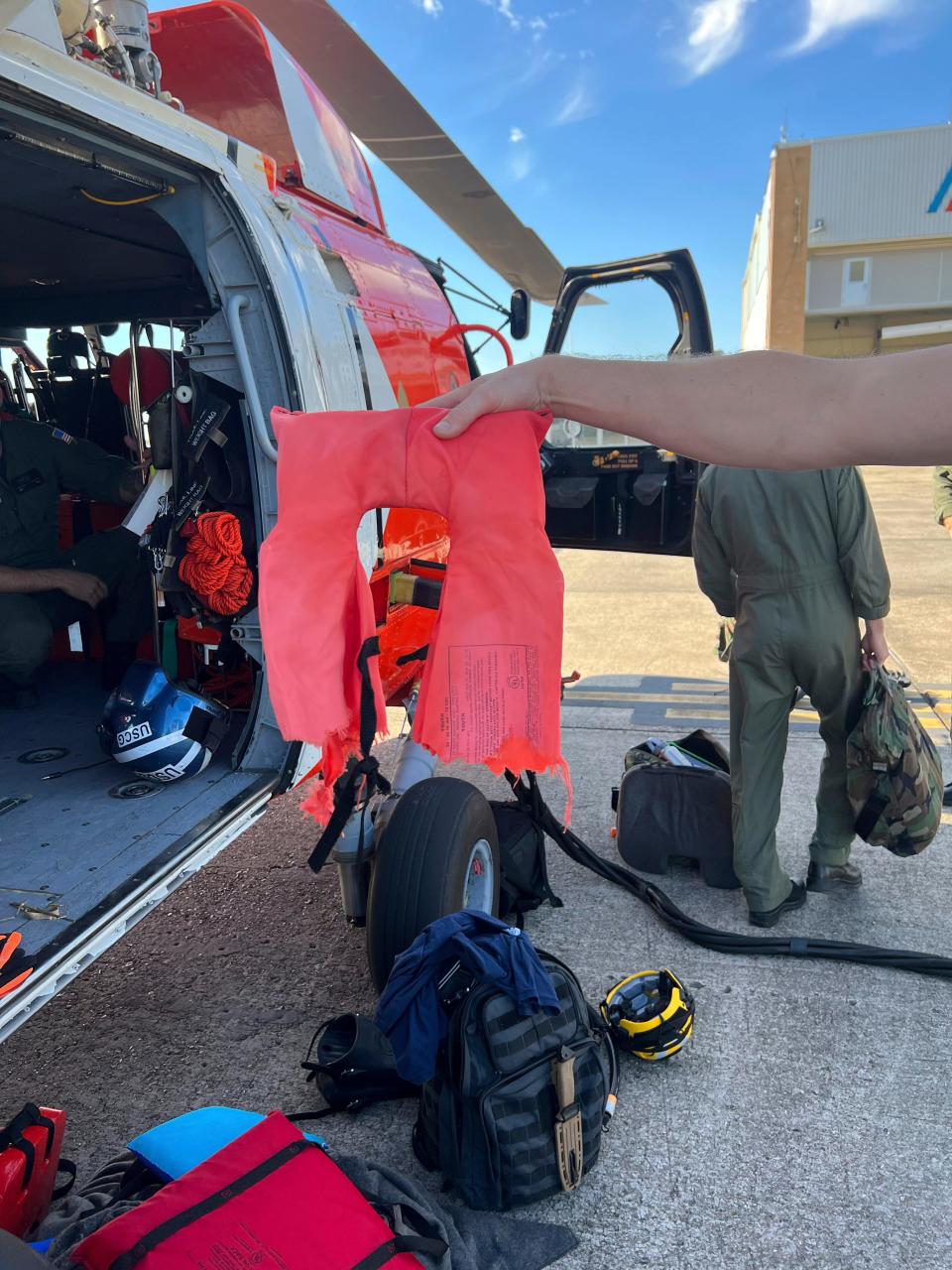 In this image provided by the U.S. Coast Guard, a Coast Guard Air Station New Orleans aircrew member holds up a torn life jacket from a recent rescue off the coast of Empire, La., on Oct. 9, 2022.