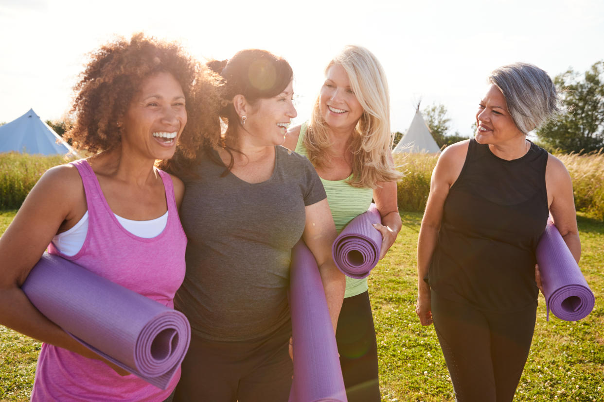 Group Of Mature Female Friends On Outdoor Yoga Retreat menopause Walking Along Path Through Campsite