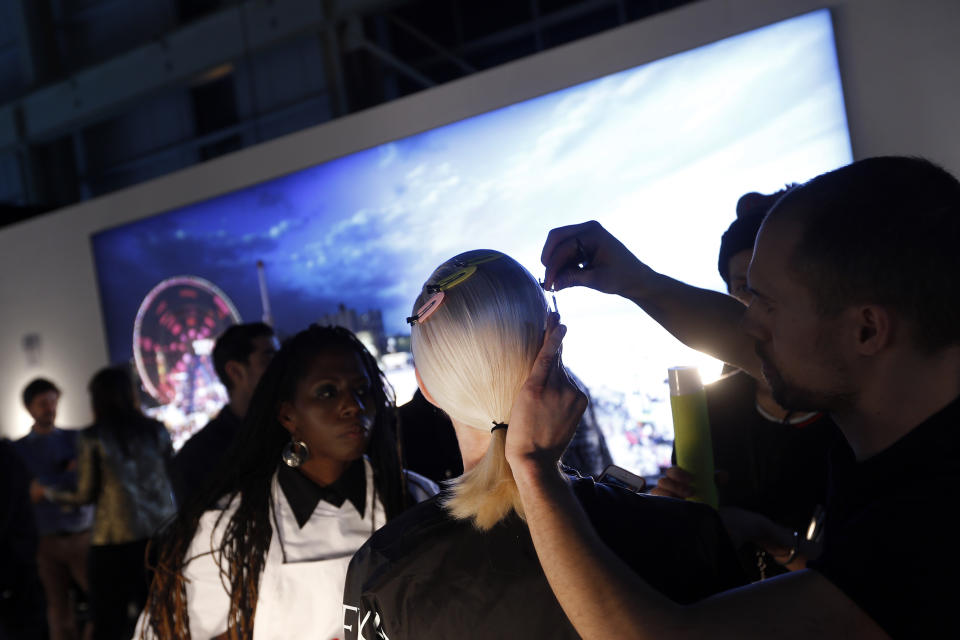 A lighted mural depicting the Coney Island boardwalk can be seen inside the Brooklyn Navy Yard's Duggal Greenhouse as a model has her hair done backstage before the Alexander Wang Fall 2014 collection show during Fashion Week in New York, Saturday, Feb. 8, 2014. (AP Photo/Jason DeCrow)