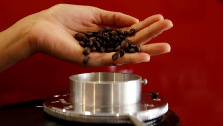 FILE PHOTO: A waitress pours coffee beans into a grinder before she prepares an expresso at a coffee bar in Sao Paulo, Brazil on February 8, 2011. REUTERS/Nacho Doce/File Photo