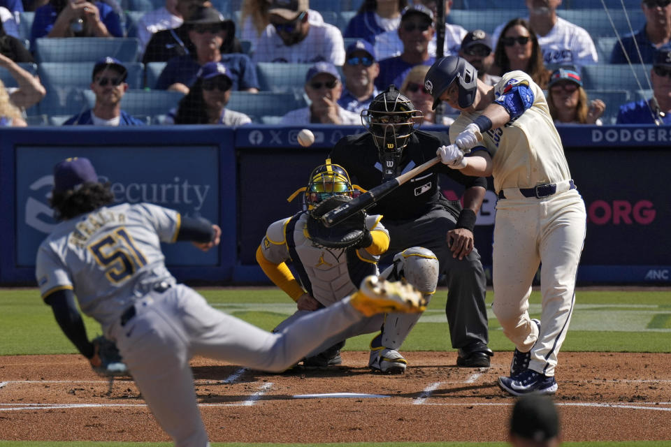 Los Angeles Dodgers' Will Smith, right, hits a two-run home run as Milwaukee Brewers starting pitcher Freddy Peralta, left, and catcher William Contreras, second from left, watch along with home plate umpire Edwin Moscoso during the first inning of a baseball game Saturday, July 6, 2024, in Los Angeles. (AP Photo/Mark J. Terrill)