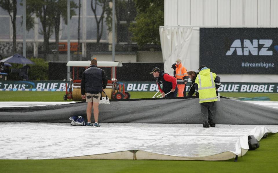 Ground staff clear surface water from the covers as rain delays play on the final day of the first cricket test between South Africa and New Zealand at University Oval, Dunedin, New Zealand, Sunday, March 12, 2017. (AP Photo/Mark Baker)