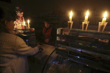 A customer visits a grocery lit with candles due to a power cut, in Simferopol, Crimea, in this November 22, 2015 file photo. REUTERS/Pavel Rebrov/Files