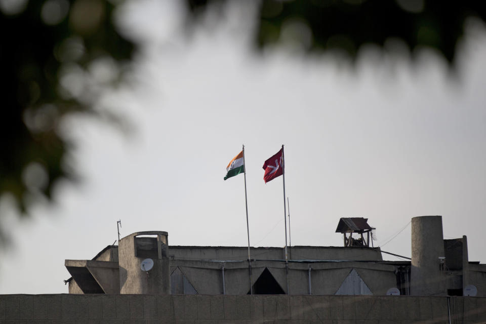FILE - An Indian national flag, left, flies next to a Jammu and Kashmir state flag on the Civil Secretariat building, in Srinagar, Indian controlled Kashmir Aug. 9, 2019. On Aug. 5, 2019, Indian Prime Minister Narendra Modi's government passed legislation in Parliament that stripped Jammu and Kashmir's statehood, scrapped its separate constitution and removed inherited protections on land and jobs. While deeply unpopular in Muslim-majority Kashmir, Modi was cheered by supporters for fulfilling a long-held Hindu nationalist pledge to scrap the restive region's special privileges and assimilate Kashmir into the rest of the country. (AP Photo/ Dar Yasin, File)