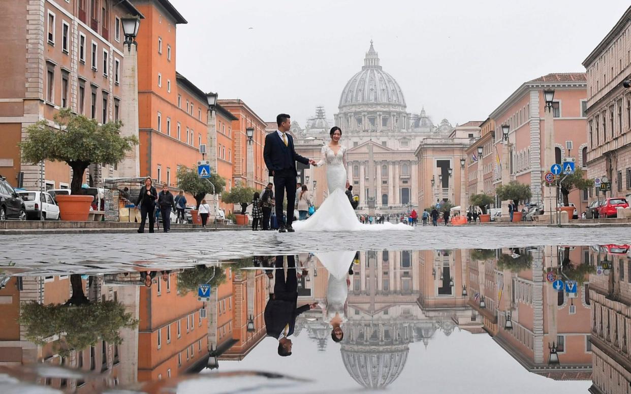 Traditional church weddings are declining in Italy. A couple in front of St Peter's Basilica in Rome - AFP