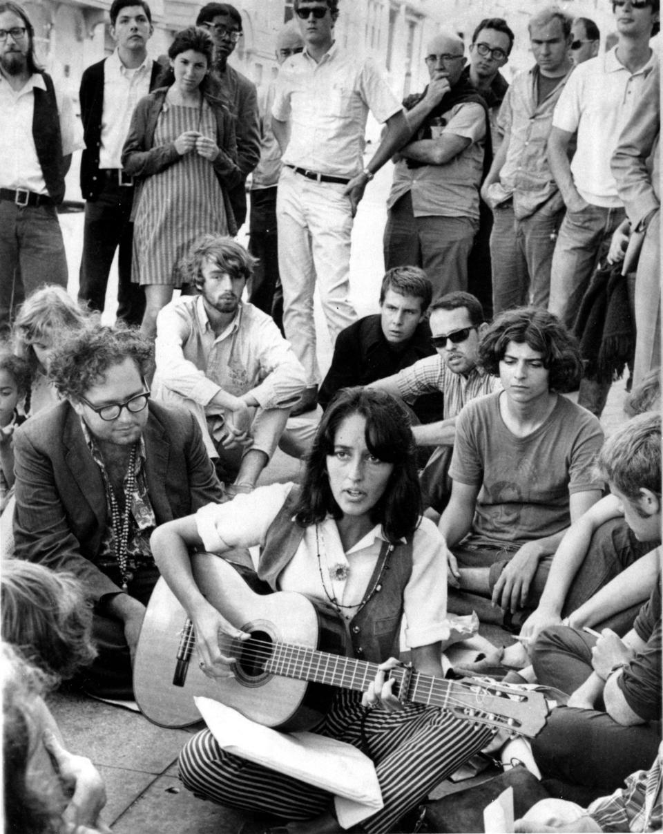 FILE - In this Sept. 22, 1967, file photo, folk singer Joan Baez sits at the corner of Haight and Ashbury in San Francisco, serenading hippies and tourists. City officials have rejected a permit for a planned free concert intended to mark the 50th anniversary of the famed Summer of Love in Golden Gate Park that had been planned for June 2017. (AP Photo/File)