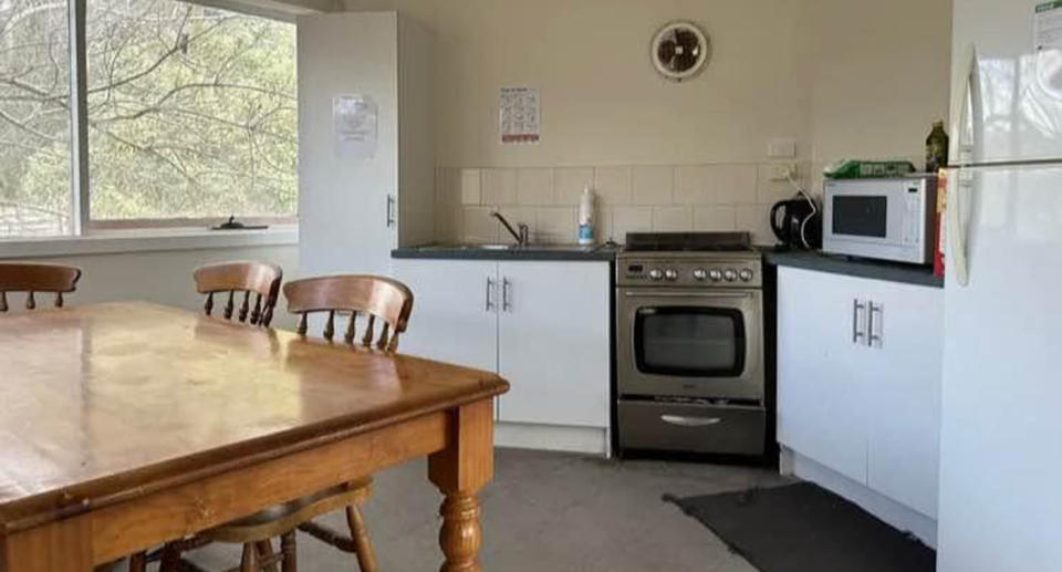 Vic rentalTimber dining table in kitchen with white cupboards.