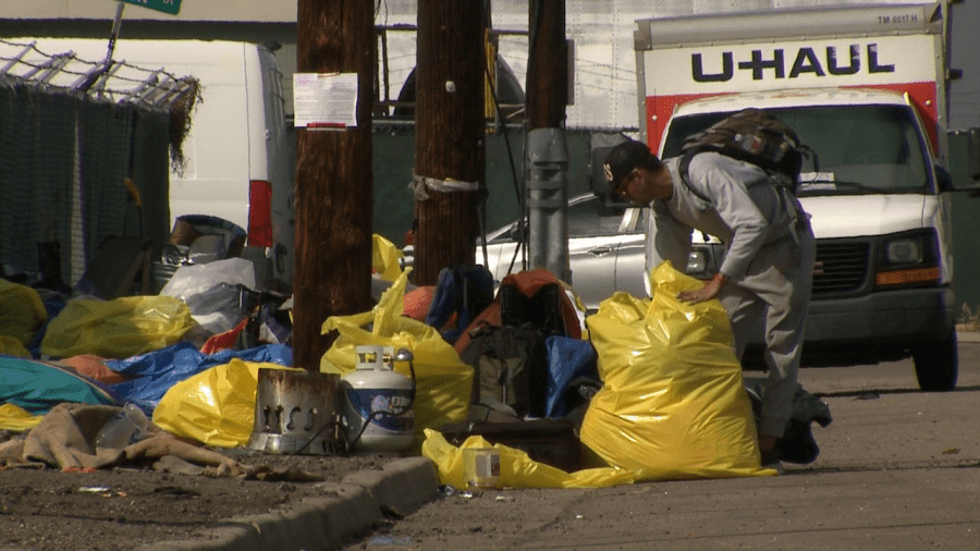 Man with backpack loads a trash bag