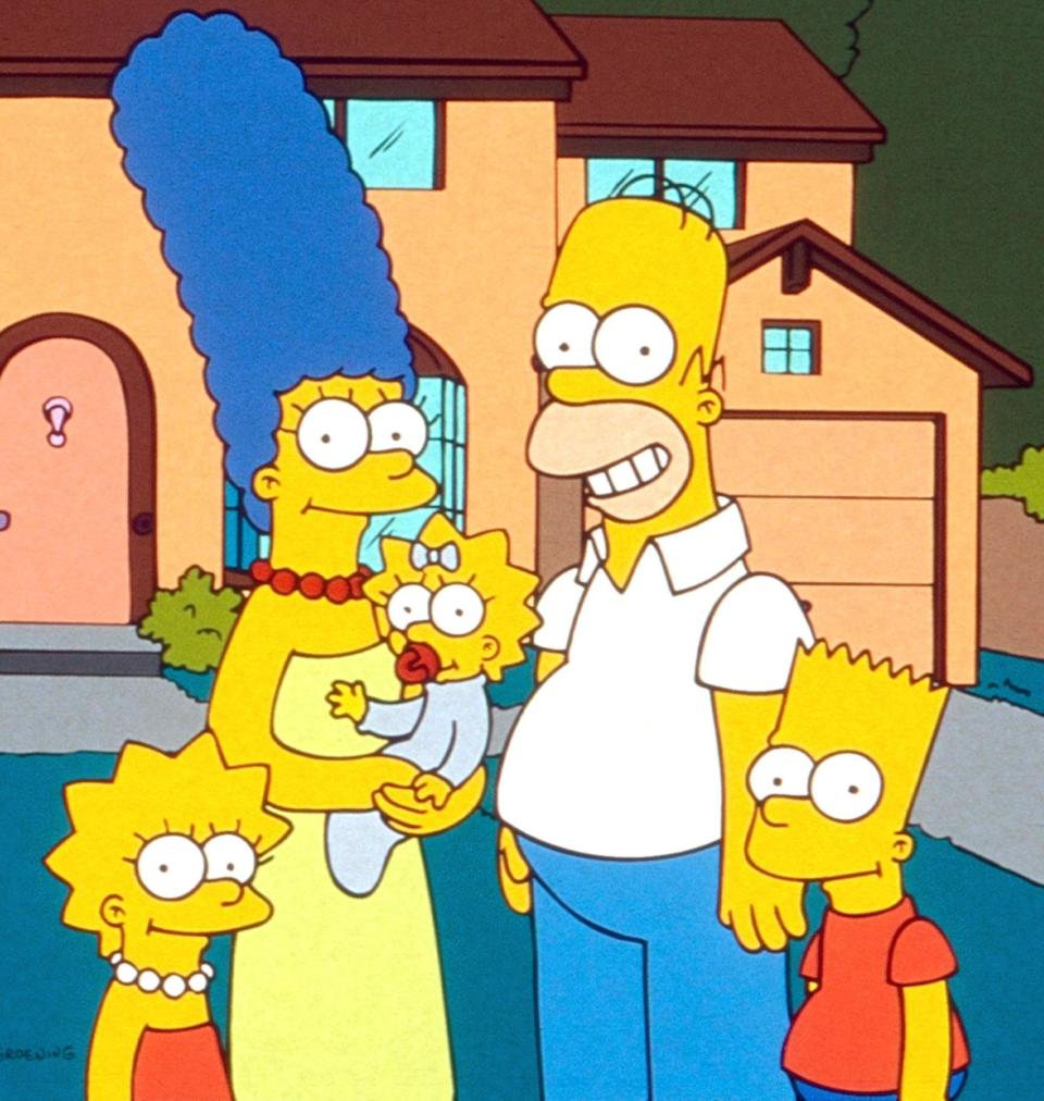 The Simpsons family standing in front of their home with Marge, Homer, Bart, Lisa, and Maggie