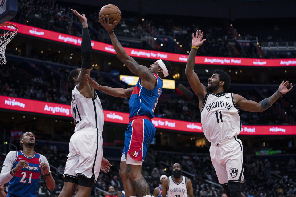 Washington Wizards guard Bradley Beal drives to the basket against Brooklyn Nets center LaMarcus Aldridge during the first half of an NBA basketball game, Wednesday, Jan. 19, 2022, in Washington. At left is Wizards center Daniel Gafford, and at right is Nets guard Kyrie Irving. (AP Photo/Evan Vucci)