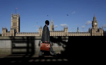 A man walks past the Houses of Parliament in London, Britain, in this May 10, 2011 file photo. REUTERS/Suzanne Plunkett/Files