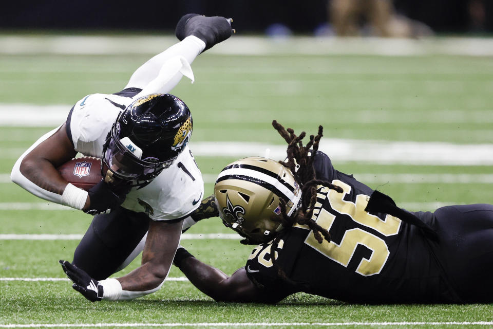 Travis Etienne Jr., corredor de los Jaguars de Jacksonville, es frenado por Demario Davis, linebacker de los Saints de Nueva Orleáns, en el partido del jueves 19 de octubre de 2023 (AP Foto/Butch Dill)