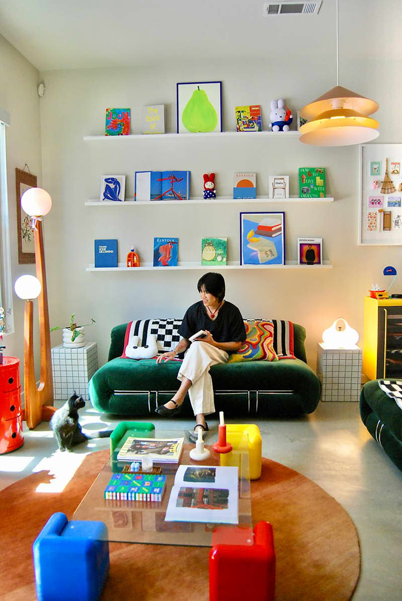 Dweller sitting on green velvet sofa in eclectic living room.