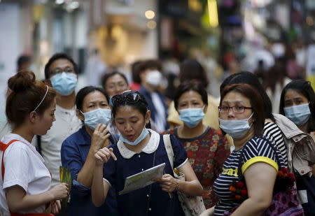 A tourist wearing a mask to prevent contracting Middle East Respiratory Syndrome (MERS) asks a sales assistant for directions as they tour Myeongdong shopping district in central Seoul, South Korea, June 12, 2015. REUTERS/Kim Hong-Ji