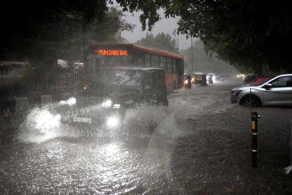 Vehicles move through a water logged street during a heavy downpour in New Delhi, India, Sunday, July 9, 2023. (AP Photo/Manish Swarup)